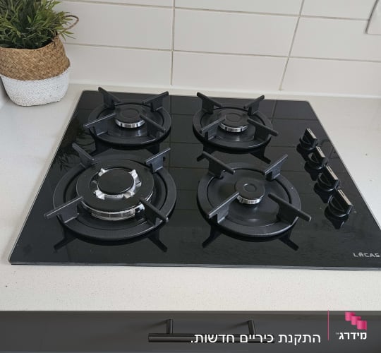 כיריים גז שחורות עם ארבעה מבערים וכפתורי שליטה
